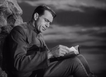 Movie still from “Sergeant York” (1941), directed by Howard Hawks – A black and white photo of a man reading a book; Medium shot, Low angle