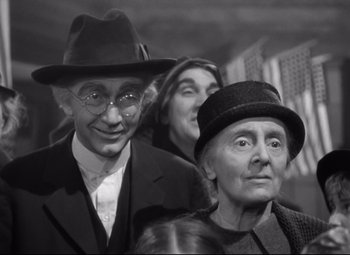 Movie still from “Sergeant York” (1941), directed by Howard Hawks – An older man and woman wearing hats and glasses; Close Up shot, Over the shoulder angle