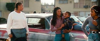 Movie still from “Set It Off” (1996), directed by F. Gary Gray – A woman holding a child next to an old car; Medium shot, Low angle