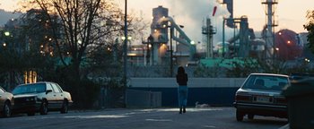 Movie still from “Set It Off” (1996), directed by F. Gary Gray – A person walking down a street near a factory; Extreme Wide shot, Over the shoulder angle