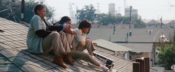 Movie still from “Set It Off” (1996), directed by F. Gary Gray – Two people sitting on a roof top looking at a phone; Wide shot, Low angle