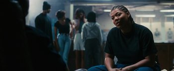 Movie still from “Set It Off” (1996), directed by F. Gary Gray – A group of people standing around a room; Medium shot, Over the shoulder angle