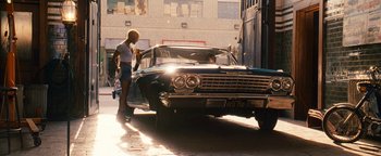Movie still from “Set It Off” (1996), directed by F. Gary Gray – A woman standing in front of an old blue car; Wide shot, Over the shoulder angle