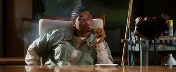 Movie still from “Set It Off” (1996), directed by F. Gary Gray – A man sitting at a table with a cigarette in his mouth; Medium shot, Low angle