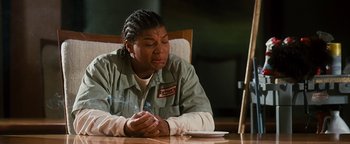 Movie still from “Set It Off” (1996), directed by F. Gary Gray – A woman sitting at a table with her hands folded over her face; Medium shot, Low angle