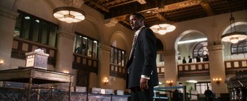 Movie still from “Set It Off” (1996), directed by F. Gary Gray – A man in a suit and tie standing in a room; Medium shot, Low angle