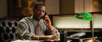 Movie still from “Set It Off” (1996), directed by F. Gary Gray – A man sitting at a desk talking on a phone; Medium shot, Low angle