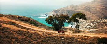 Movie still from “Set It Off” (1996), directed by F. Gary Gray – A truck driving down a dirt road next to a body of water; Extreme Wide shot, High angle