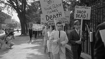 Movie still from “Seven Days in May” (1964), directed by John Frankenheimer – A black and white photo of people holding placards; Medium shot, High angle