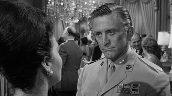 Movie still from “Seven Days in May” (1964), directed by John Frankenheimer – A man in a military uniform talking to a woman in a crowd; Close Up shot, Over the shoulder angle