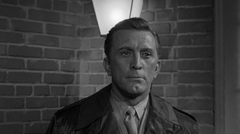 Movie still from “Seven Days in May” (1964), directed by John Frankenheimer – A black and white photo of a man wearing a jacket and tie; Close Up shot, Low angle