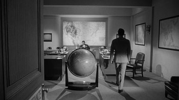Movie still from “Seven Days in May” (1964), directed by John Frankenheimer – A man and a woman in a room with a globe; Wide shot, High angle