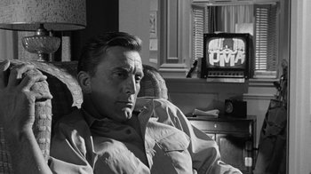 Movie still from “Seven Days in May” (1964), directed by John Frankenheimer – A black and white photo of a man sitting in front of a tv; Close Up shot, Over the shoulder angle