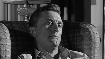 Movie still from “Seven Days in May” (1964), directed by John Frankenheimer – An older man sitting on a couch with his hand on his chin; Close Up shot, Low angle