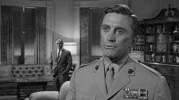 Movie still from “Seven Days in May” (1964), directed by John Frankenheimer – A man in a military uniform standing next to another man in a suit and tie; Close Up shot, Over the shoulder angle