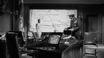 Movie still from “Seven Days in May” (1964), directed by John Frankenheimer – An old photo of two men standing in front of a map; Wide shot, Low angle