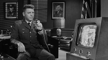 Movie still from “Seven Days in May” (1964), directed by John Frankenheimer – A man in a military uniform holding a remote control; Medium shot, Over the shoulder angle