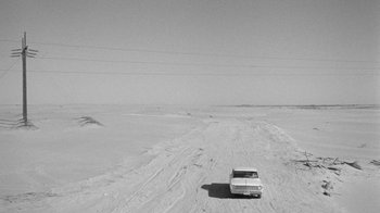Movie still from “Seven Days in May” (1964), directed by John Frankenheimer – A car is driving through the snow on a road; Extreme Wide shot, High angle
