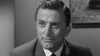 Movie still from “Seven Days in May” (1964), directed by John Frankenheimer – An older man in a suit and tie looking at the camera; Close Up shot, Over the shoulder angle
