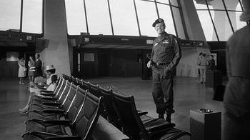 Movie still from “Seven Days in May” (1964), directed by John Frankenheimer – A man in uniform standing in front of a row of chairs; Wide shot, Low angle