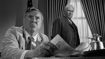 Movie still from “Seven Days in May” (1964), directed by John Frankenheimer – Two men in suits and ties are looking at papers; Medium shot, Low angle