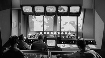 Movie still from “Seven Days in May” (1964), directed by John Frankenheimer – A group of people in front of a television screen; Wide shot, High angle