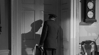 Movie still from “Seven Days in May” (1964), directed by John Frankenheimer – A black and white photo of a man holding a briefcase; Medium shot, Over the shoulder angle