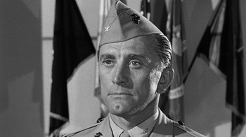 Movie still from “Seven Days in May” (1964), directed by John Frankenheimer – An old photo of a man in a military uniform looking straight ahead; Close Up shot, Low angle