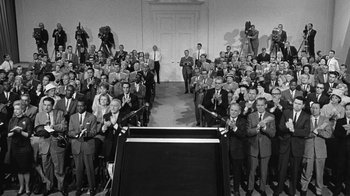 Movie still from “Seven Days in May” (1964), directed by John Frankenheimer – A large group of people standing in front of a podium; Wide shot, High angle