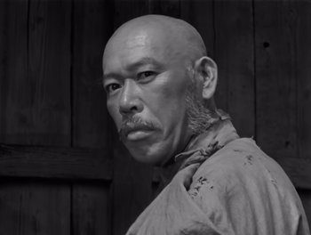 Movie still from “Seven Samurai” (1954), directed by Akira Kurosawa – An older man with a shaved head and a beard; Close Up shot, Low angle