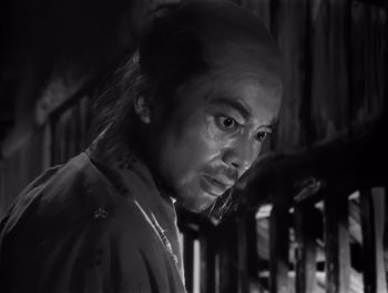 Movie still from “Seven Samurai” (1954), directed by Akira Kurosawa – A man with a long black hair and a black shirt; Close Up shot, Low angle