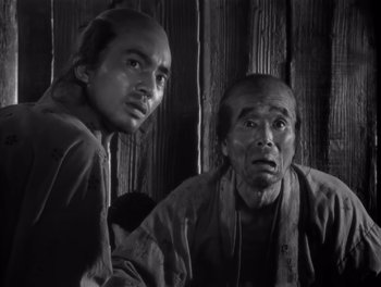 Movie still from “Seven Samurai” (1954), directed by Akira Kurosawa – A couple of men standing next to each other in a room; Medium shot, Low angle