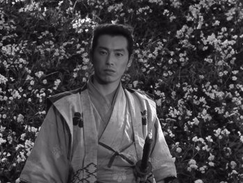 Movie still from “Seven Samurai” (1954), directed by Akira Kurosawa – A man in a kimono standing in front of a bush; Medium shot, Low angle