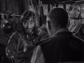 Movie still from “Seven Samurai” (1954), directed by Akira Kurosawa – A man in a samurai outfit talking to another man; Medium shot, Over the shoulder angle