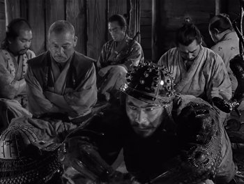 Movie still from “Seven Samurai” (1954), directed by Akira Kurosawa – A black and white photo of a group of men sitting in a room; Medium shot, High angle
