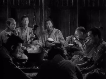 Movie still from “Seven Samurai” (1954), directed by Akira Kurosawa – A black and white photo of a group of people eating; Medium shot, High angle