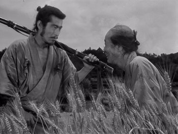 Movie still from “Seven Samurai” (1954), directed by Akira Kurosawa – Two men in traditional japanese garb in a wheat field; Medium shot, Low angle