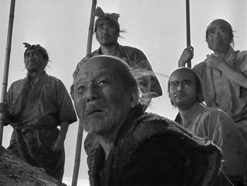 Movie still from “Seven Samurai” (1954), directed by Akira Kurosawa – A group of men standing next to each other holding poles; Medium shot, Low angle