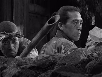 Movie still from “Seven Samurai” (1954), directed by Akira Kurosawa – A man holding a baseball bat over his head; Medium shot, Low angle