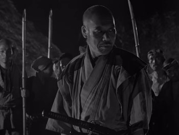 Movie still from “Seven Samurai” (1954), directed by Akira Kurosawa – A black and white photo of a man holding a sword; Medium shot, Low angle