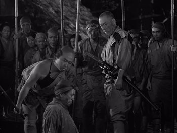 Movie still from “Seven Samurai” (1954), directed by Akira Kurosawa – A group of men standing next to each other holding guns; Medium shot, High angle