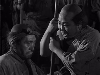 Movie still from “Seven Samurai” (1954), directed by Akira Kurosawa – Two men in traditional japanese garb , one of which has an arrow in it's head; Medium shot, High angle