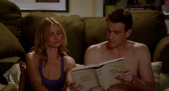 Movie still from “Sex Tape” (2014), directed by Jake Kasdan – A man and a woman sitting on a couch looking at a book; Medium shot, High angle