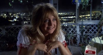 Movie still from “Shampoo” (1975), directed by Hal Ashby – A woman smiling for the camera on a balcony; Close Up shot, Over the shoulder angle
