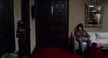 Movie still from “Shampoo” (1975), directed by Hal Ashby – A woman sitting on a chair in front of an open door; Wide shot, High angle