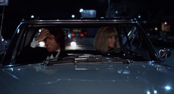 Movie still from “Shampoo” (1975), directed by Hal Ashby – A man and a woman in the back seat of a car; Medium shot, Over the shoulder angle