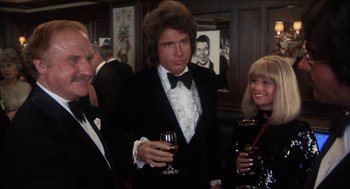 Movie still from “Shampoo” (1975), directed by Hal Ashby – A man in a tuxedo standing next to two other people; Medium shot, Over the shoulder angle