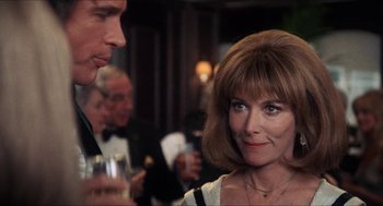 Movie still from “Shampoo” (1975), directed by Hal Ashby – A man and a woman talking to each other in front of a crowd; Close Up shot, Over the shoulder angle