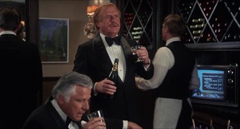 Movie still from “Shampoo” (1975), directed by Hal Ashby – A man in a tuxedo holding a bottle of champagne; Medium shot, Over the shoulder angle