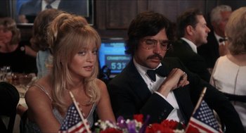 Movie still from “Shampoo” (1975), directed by Hal Ashby – A man and a woman sitting next to each other at a table; Medium shot, Low angle